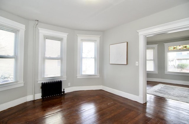 unfurnished room featuring radiator and dark hardwood / wood-style flooring