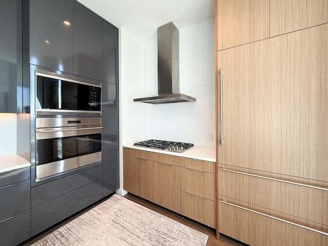 188 Brookline Ave Unit Ph28C, Boston, MA 02215 - kitchen with appliances with stainless steel finishes, wall chimney range hood, light countertops, wood finished floors, and modern cabinets