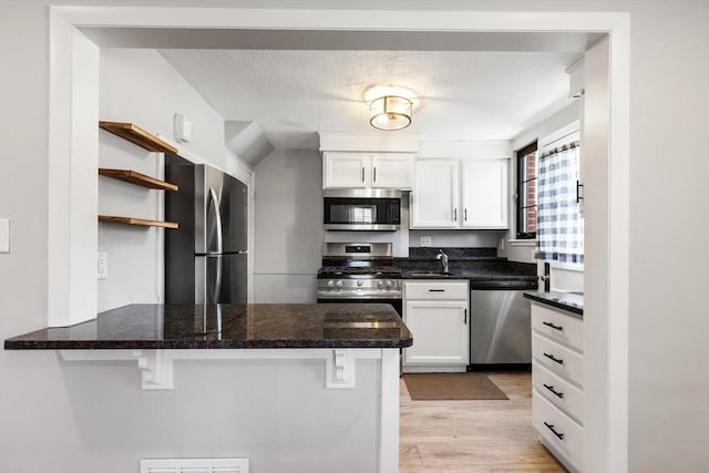 kitchen with a peninsula, appliances with stainless steel finishes, white cabinets, and a kitchen breakfast bar