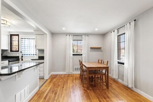 dining area with visible vents, light wood-style flooring, and baseboards