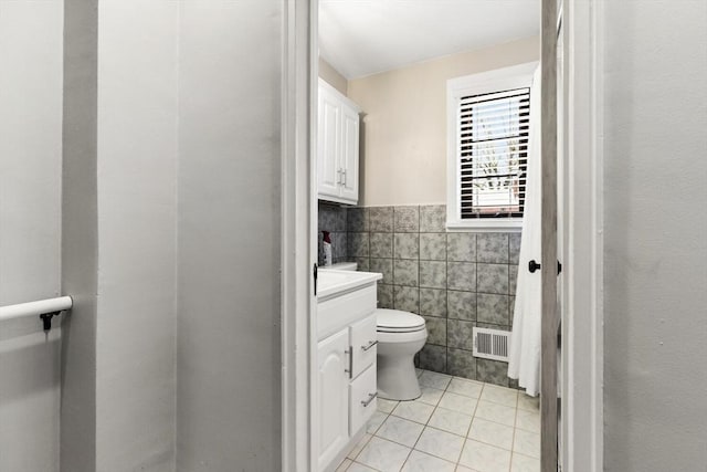 half bathroom featuring visible vents, vanity, wainscoting, tile walls, and tile patterned floors