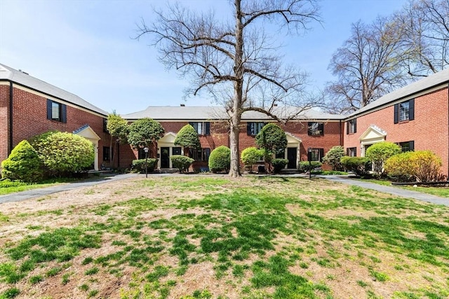 view of front of home featuring brick siding and a front yard