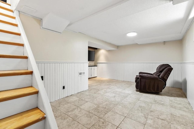 unfurnished room featuring stairway, a wainscoted wall, and visible vents