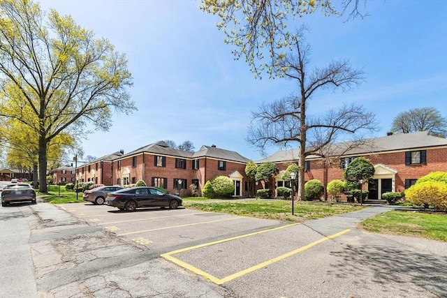 view of front of house with brick siding, a residential view, and uncovered parking