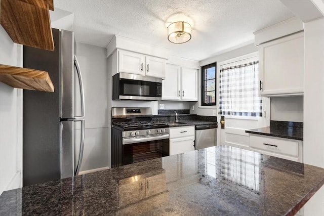 kitchen featuring a sink, a textured ceiling, stainless steel appliances, and white cabinetry