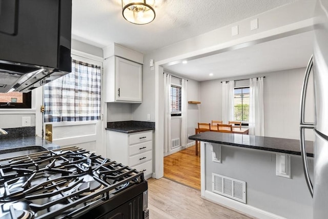kitchen with visible vents, freestanding refrigerator, light wood finished floors, and gas stove