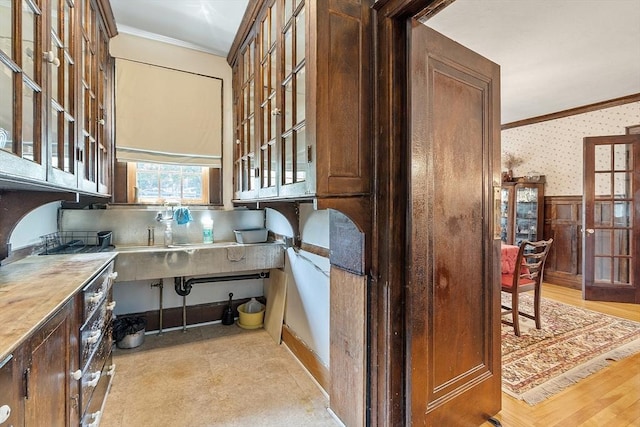 298 Highland St, Worcester, MA 01602 - kitchen featuring crown molding, wainscoting, wallpapered walls, and glass insert cabinets