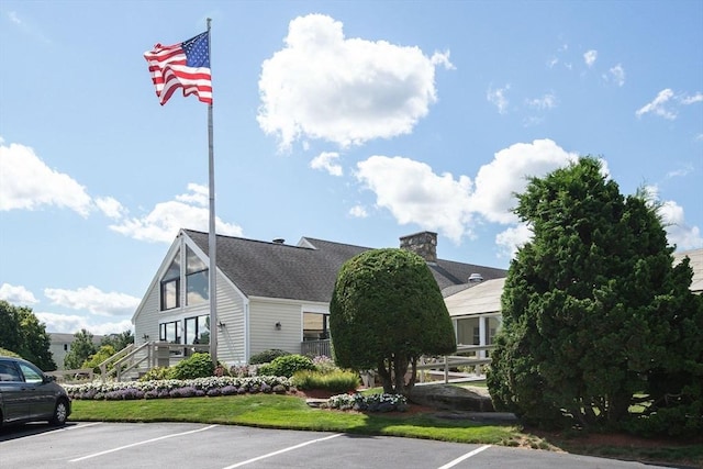 exterior space featuring uncovered parking, a chimney, and a front yard