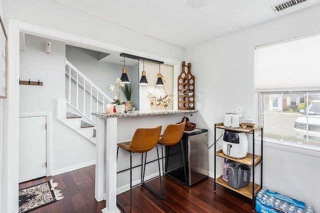 bar featuring baseboards, visible vents, stairway, hardwood / wood-style floors, and pendant lighting