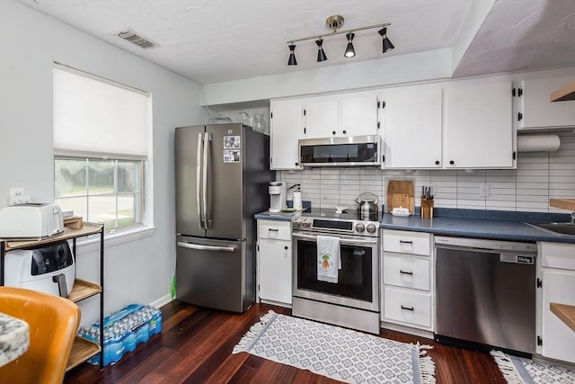 kitchen with appliances with stainless steel finishes, dark countertops, dark wood finished floors, and backsplash