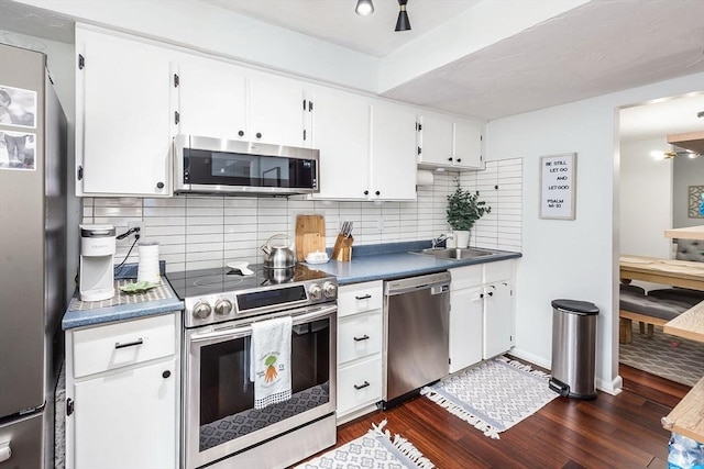 kitchen featuring dark wood-style floors, stainless steel appliances, dark countertops, and decorative backsplash