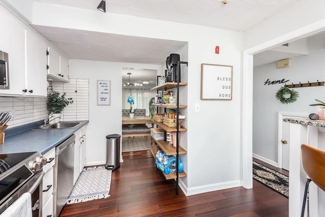 kitchen featuring tasteful backsplash, dark wood-style floors, appliances with stainless steel finishes, white cabinetry, and a sink