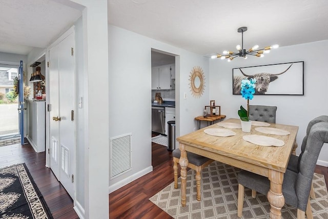 dining room featuring baseboards, wood finished floors, visible vents, and a notable chandelier