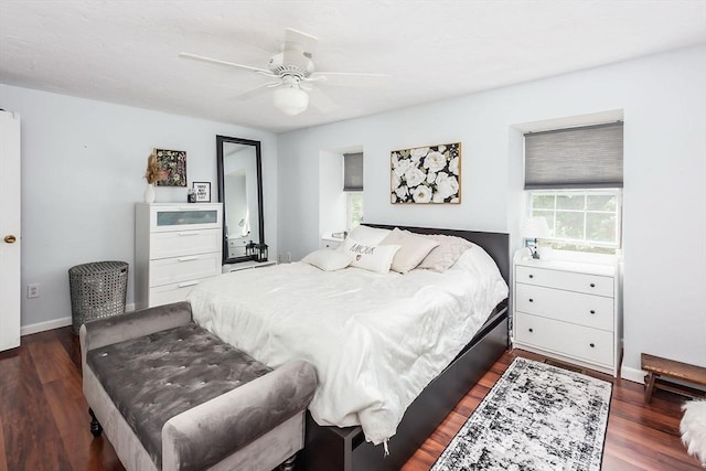 bedroom with dark wood-style floors, multiple windows, baseboards, and a ceiling fan