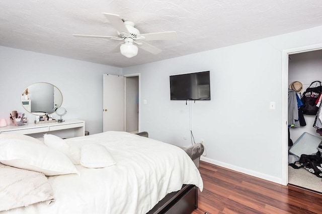 bedroom with a ceiling fan, a textured ceiling, baseboards, and wood finished floors