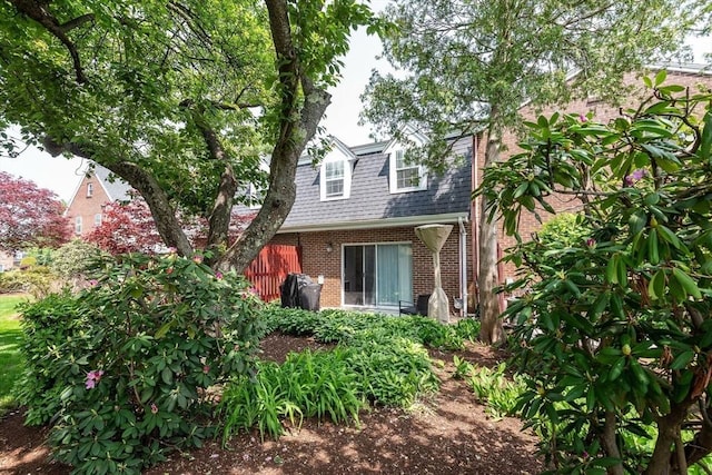 view of front of property with a shingled roof and brick siding