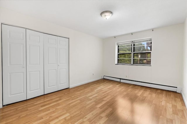 4925 Washington St Unit 304, Boston, MA 02132 - unfurnished bedroom featuring a baseboard heating unit, light wood finished floors, and a closet