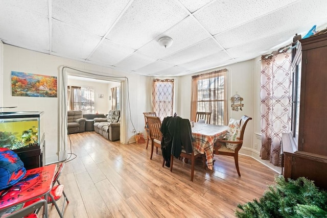 dining space with a paneled ceiling and light hardwood / wood-style flooring