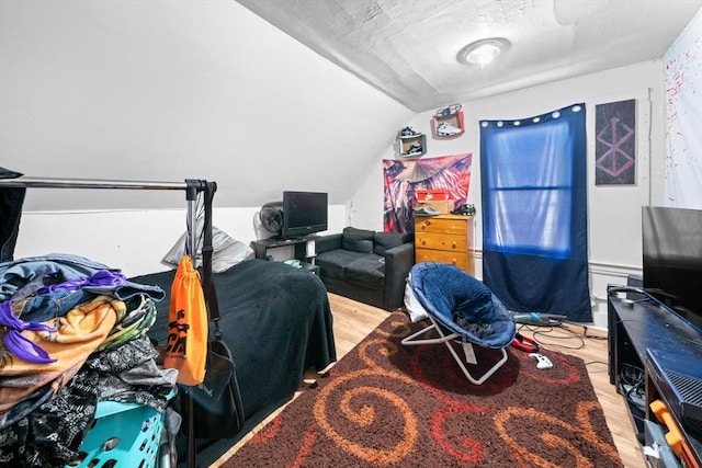 bedroom featuring a textured ceiling, light hardwood / wood-style flooring, and lofted ceiling