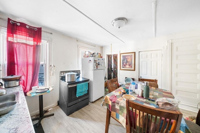 kitchen with light hardwood / wood-style floors, sink, white fridge, and stainless steel range with electric cooktop