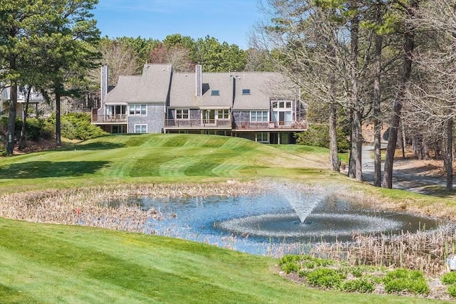 back of house with a lawn, golf course view, and a deck with water view