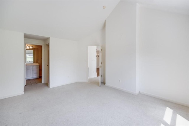 unfurnished bedroom featuring connected bathroom, vaulted ceiling, and light carpet