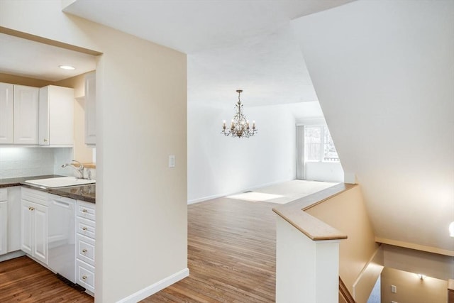 kitchen featuring a chandelier, white cabinets, a sink, light wood finished floors, and dishwasher