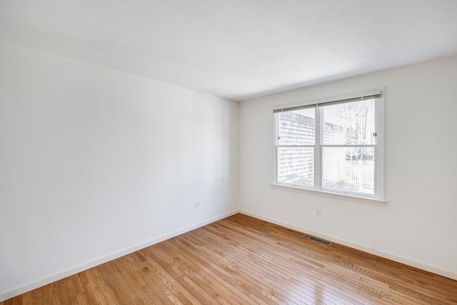 spare room with baseboards, light wood-type flooring, and visible vents