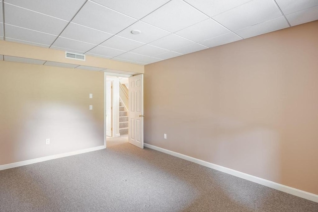 empty room featuring stairs, baseboards, carpet flooring, and a paneled ceiling