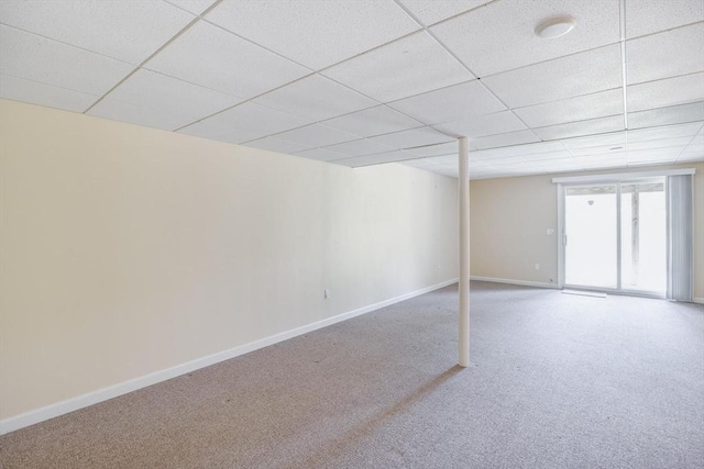 below grade area with carpet floors, baseboards, and a paneled ceiling