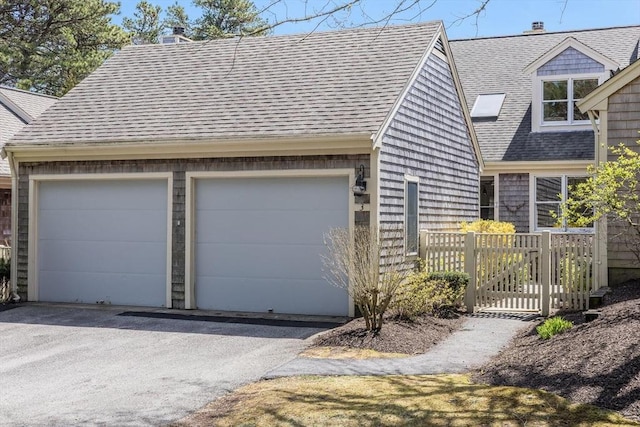 cape cod-style house featuring fence, a shingled roof, and a chimney