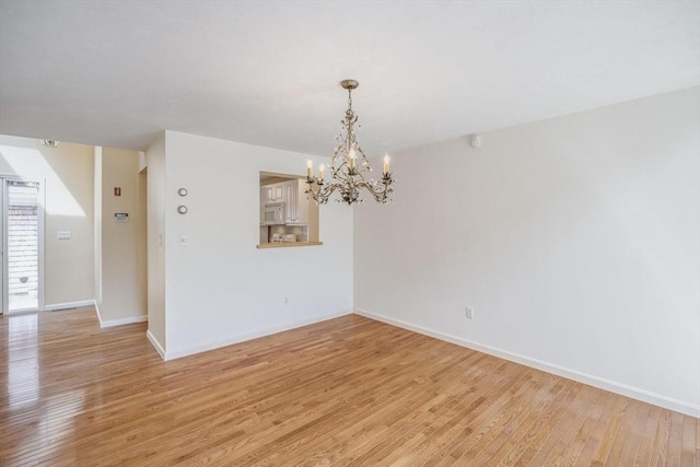unfurnished dining area with light wood-style floors, baseboards, and a chandelier