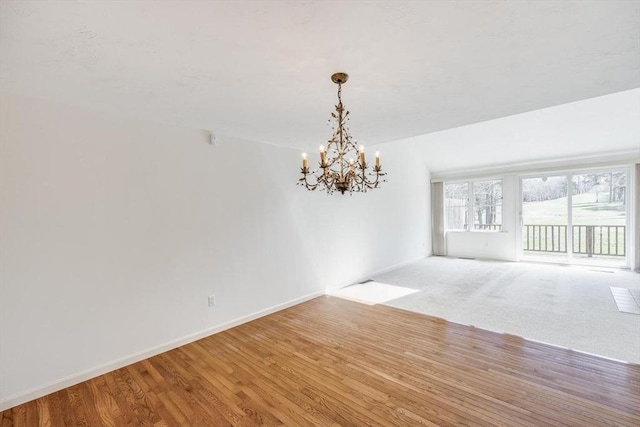 unfurnished dining area with baseboards, wood finished floors, and a notable chandelier