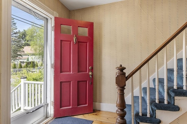 foyer with wallpapered walls, wood finished floors, and stairway