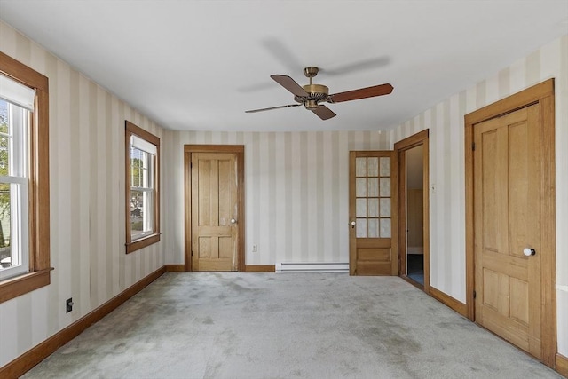 carpeted empty room featuring plenty of natural light, baseboards, baseboard heating, and wallpapered walls