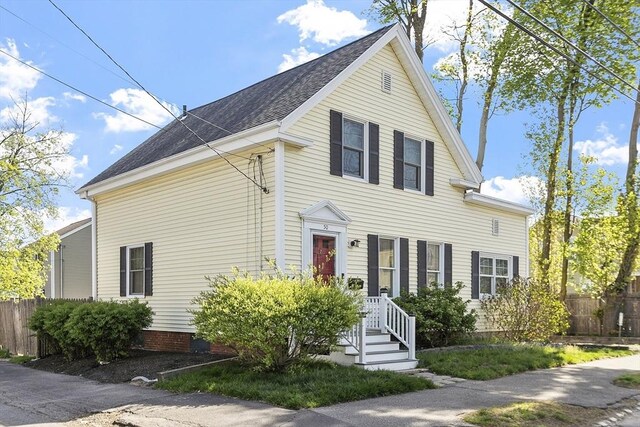 traditional home featuring fence and roof with shingles