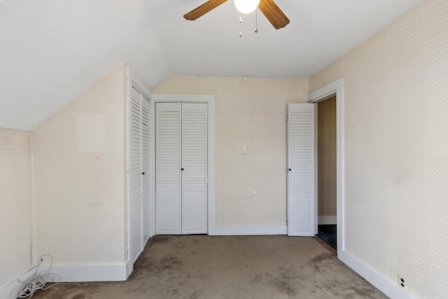 unfurnished bedroom with a closet, a ceiling fan, lofted ceiling, wallpapered walls, and carpet flooring