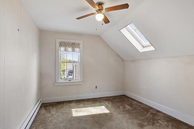 bonus room featuring ceiling fan, vaulted ceiling with skylight, carpet floors, baseboards, and a baseboard heating unit