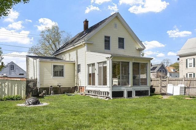 back of property with a yard, fence, a chimney, and a sunroom