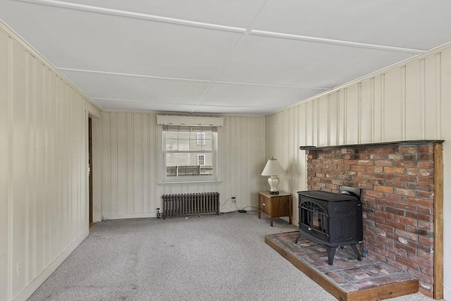 carpeted living room featuring a wood stove and radiator