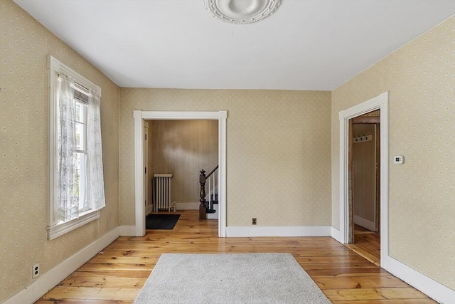 unfurnished room featuring radiator and hardwood / wood-style floors
