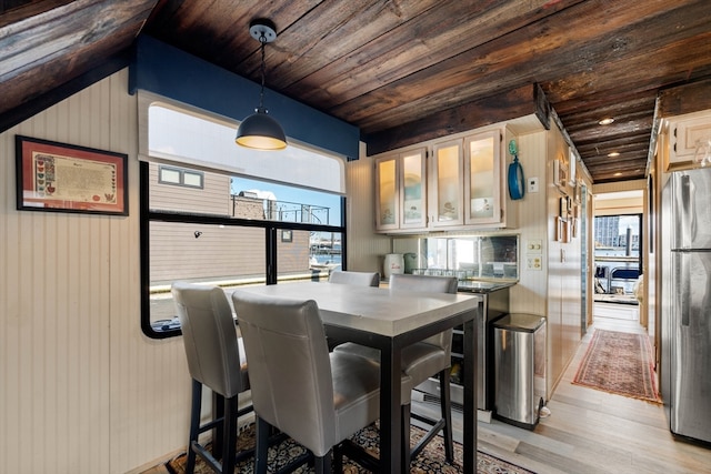 dining area featuring wood walls, wooden ceiling, light wood-type flooring, and a wealth of natural light