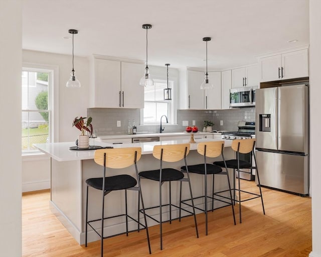 kitchen with stainless steel appliances, light hardwood / wood-style flooring, a kitchen island, and white cabinets