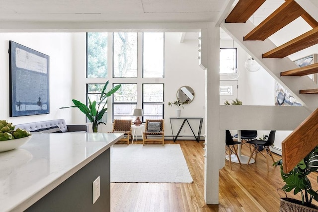 office space featuring baseboard heating, high vaulted ceiling, light hardwood / wood-style flooring, and beamed ceiling