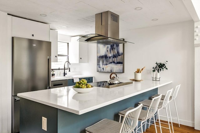 kitchen featuring island range hood, high end refrigerator, kitchen peninsula, and white cabinets