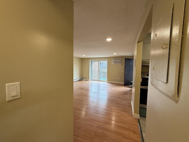 1186 Worcester Rd Unit 1221, Framingham, MA 01702 - corridor featuring a wall mounted air conditioner, light wood-style flooring, baseboards, a baseboard heating unit, and a textured ceiling