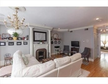 living room featuring an inviting chandelier, light wood-type flooring, and ornamental molding