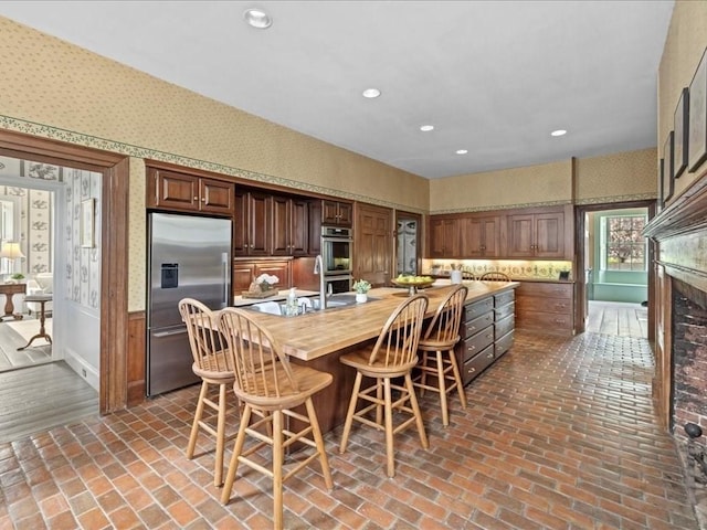 kitchen with appliances with stainless steel finishes, sink, a kitchen bar, and butcher block countertops