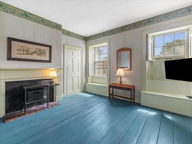 unfurnished room with wood-type flooring, plenty of natural light, and a wood stove