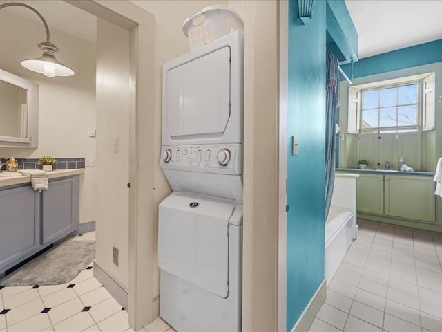 clothes washing area featuring stacked washer and dryer, light tile patterned floors, and sink